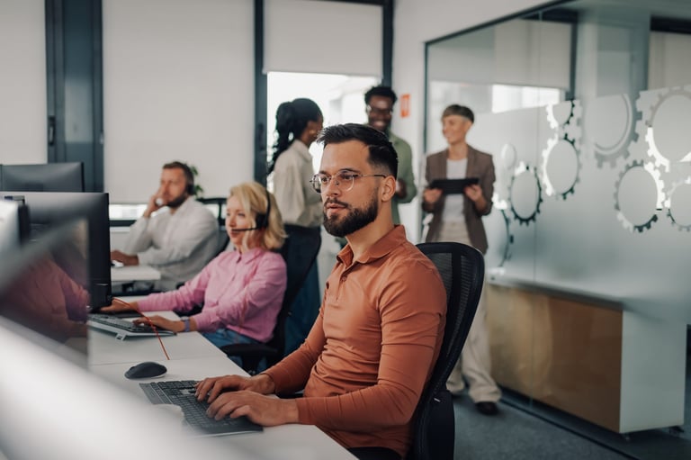 In a bustling call center a male operator concentrates on his computer
