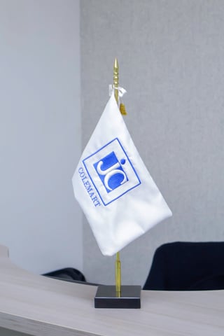 White desk flag with blue company logo mounted on gold pole with black base