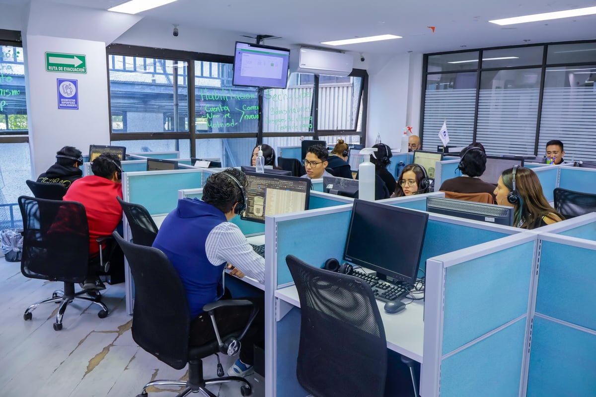 Office environment with multiple employees working at cubicles and desk stations with computers and monitors