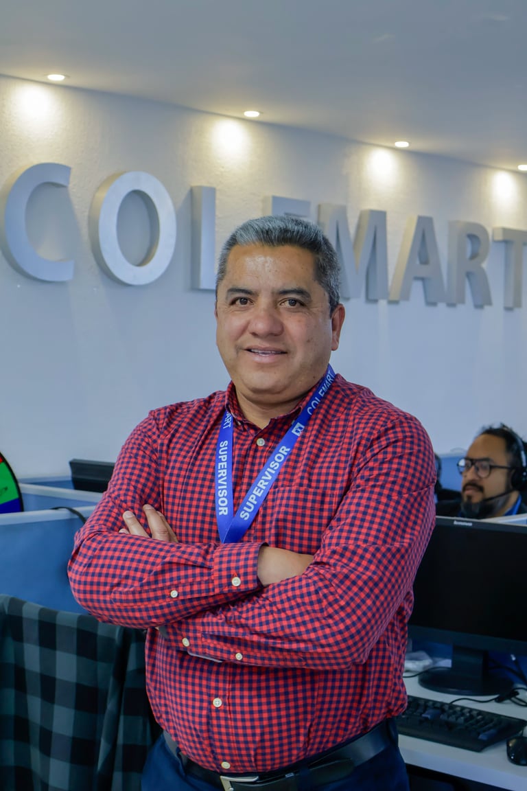 Man in red checkered shirt with ID badge standing in front of Walmart sign with arms crossed